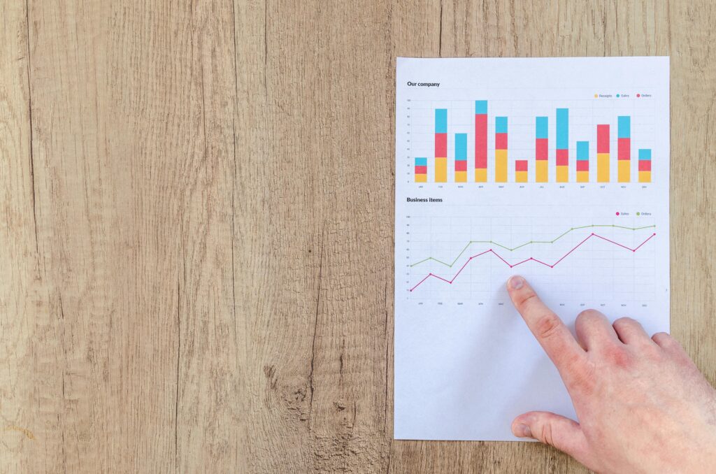 benchmarking zalety – analiza wykresów wyników firmy wskazywanych palcem na raporcie biznesowym podczas porównywania wyników z konkurencją